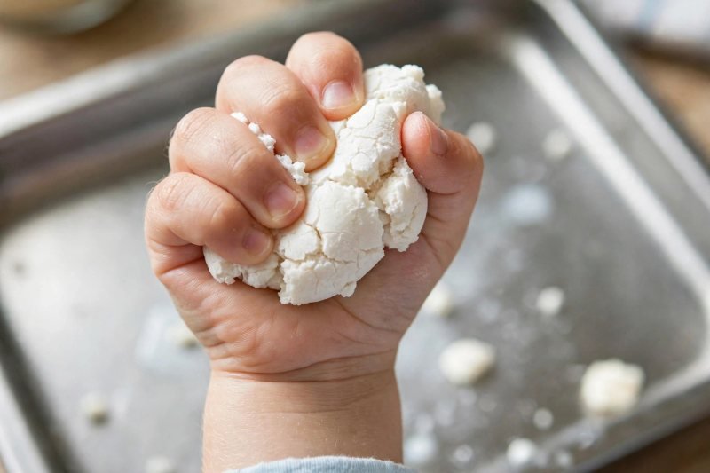 Small child's fist squeezing oobleck so the cornflour mixture holds solid